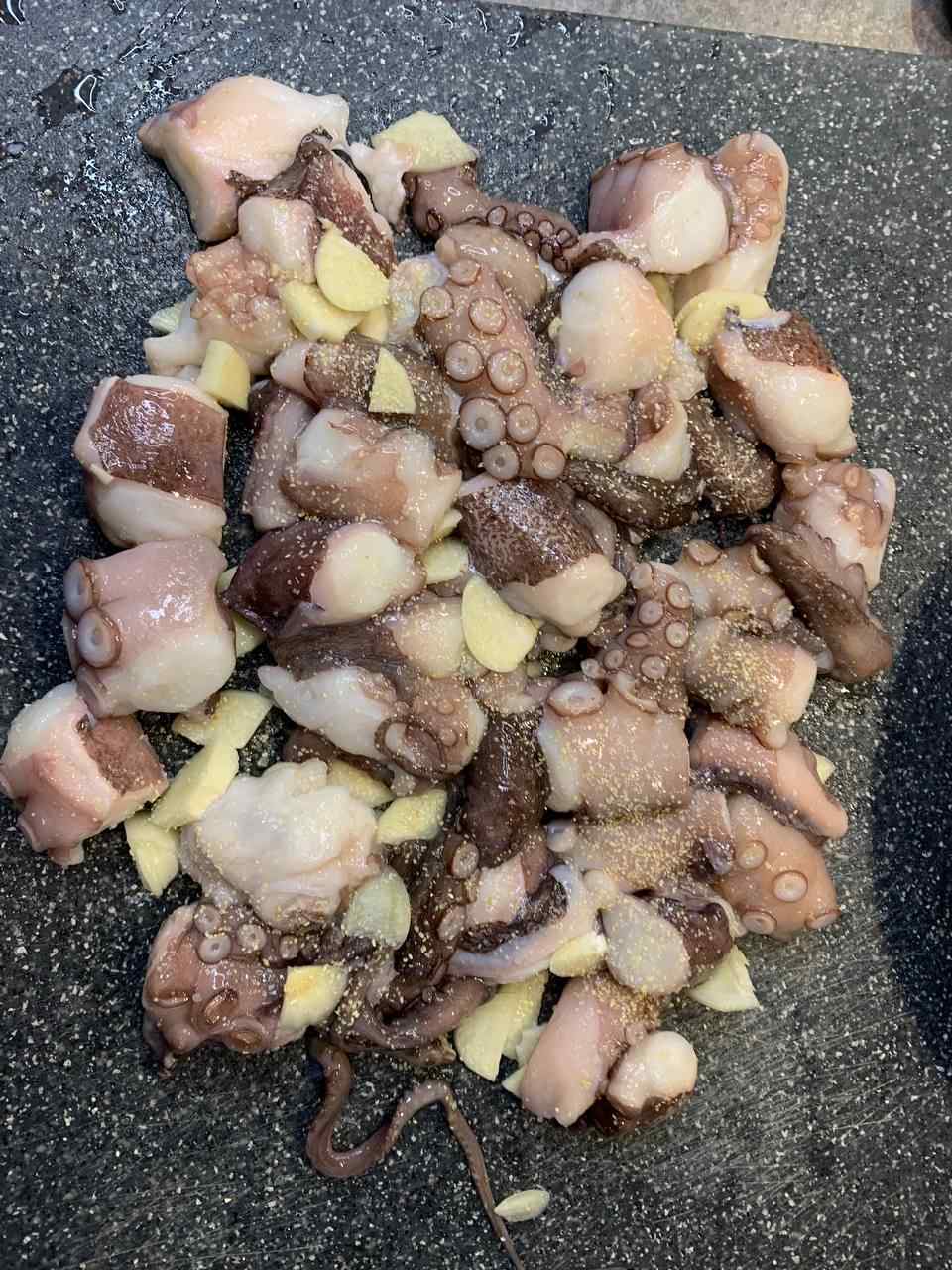Oktopus Tentakel in Würfel geschnitten und mit Knoblauch und Olivenöl vermischt